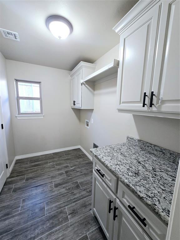 clothes washing area featuring hookup for a washing machine and cabinets