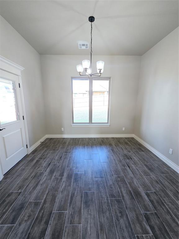 unfurnished dining area featuring a notable chandelier, dark hardwood / wood-style floors, and plenty of natural light