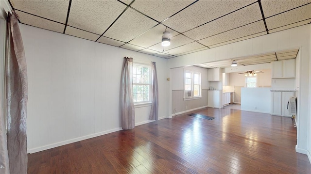 unfurnished living room featuring a paneled ceiling, dark hardwood / wood-style floors, and ceiling fan