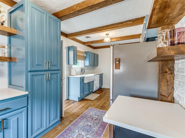 kitchen featuring white dishwasher, blue cabinets, sink, light wood-type flooring, and beamed ceiling