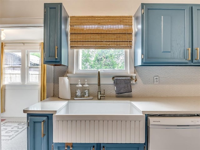 kitchen with blue cabinetry, a wealth of natural light, sink, and white dishwasher