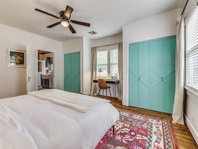 bedroom with multiple windows, dark hardwood / wood-style flooring, and ceiling fan