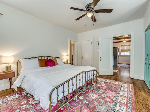 bedroom with stainless steel refrigerator, ceiling fan, and dark wood-type flooring