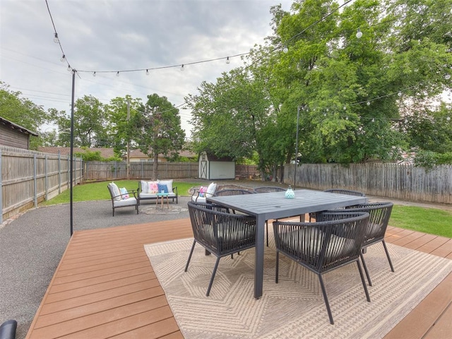 wooden deck with a lawn, an outdoor living space, and a storage shed