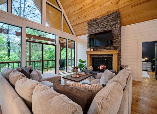 living room featuring a wealth of natural light, a fireplace, wood-type flooring, and wooden walls