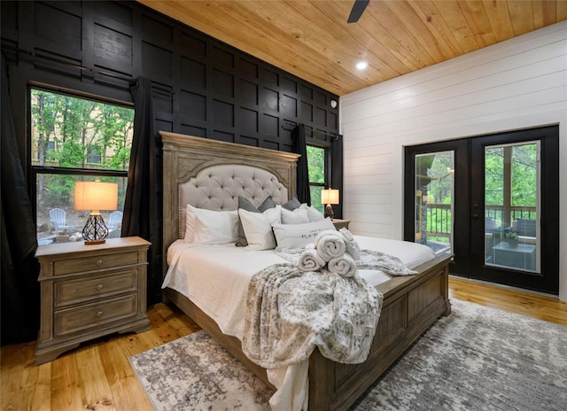 bedroom featuring wood walls, wooden ceiling, ceiling fan, access to exterior, and light wood-type flooring