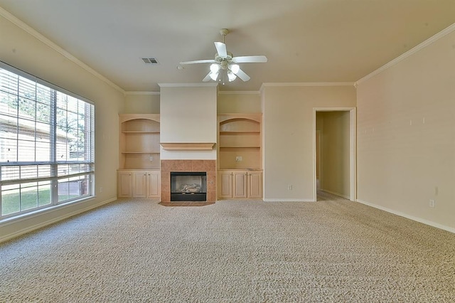 unfurnished living room with ceiling fan, a fireplace, carpet floors, and crown molding