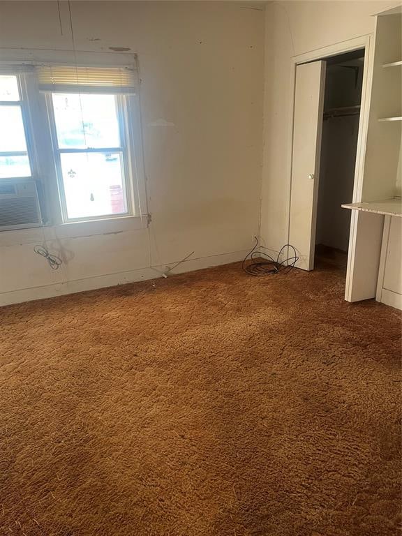 unfurnished bedroom with carpet floors, a closet, and cooling unit