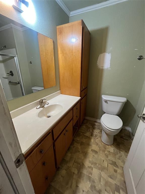 bathroom with vanity, toilet, a shower with shower door, and crown molding