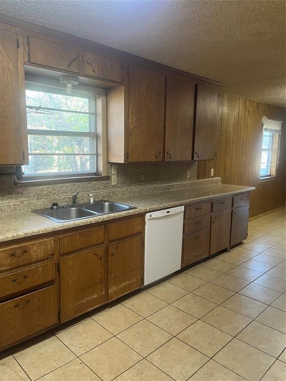 kitchen with dishwasher, light tile patterned floors, a textured ceiling, and sink