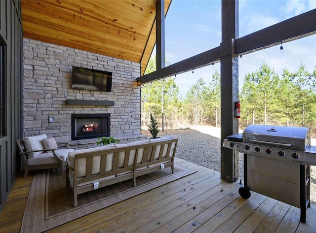 wooden terrace with an outdoor living space with a fireplace and area for grilling