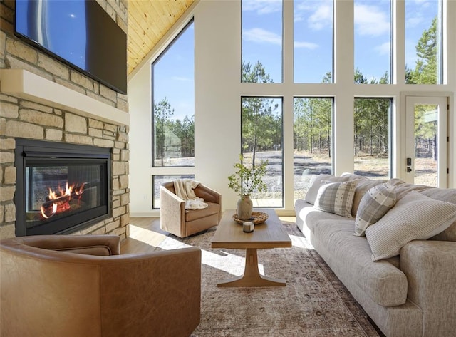 sunroom / solarium featuring a stone fireplace, wood ceiling, and a wealth of natural light