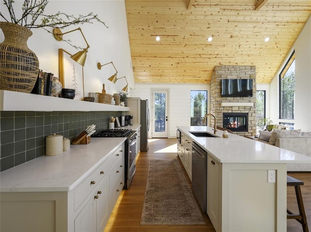 kitchen featuring sink, wooden ceiling, a center island with sink, and appliances with stainless steel finishes