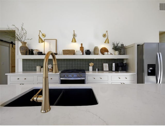 kitchen featuring decorative backsplash, a barn door, sink, and appliances with stainless steel finishes