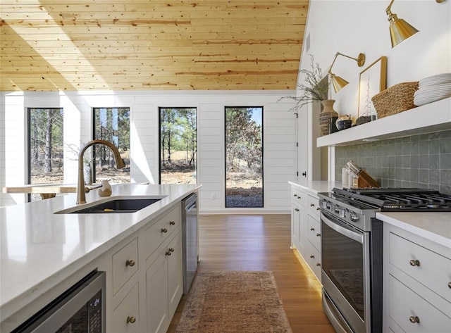 kitchen featuring backsplash, stainless steel appliances, white cabinetry, and sink