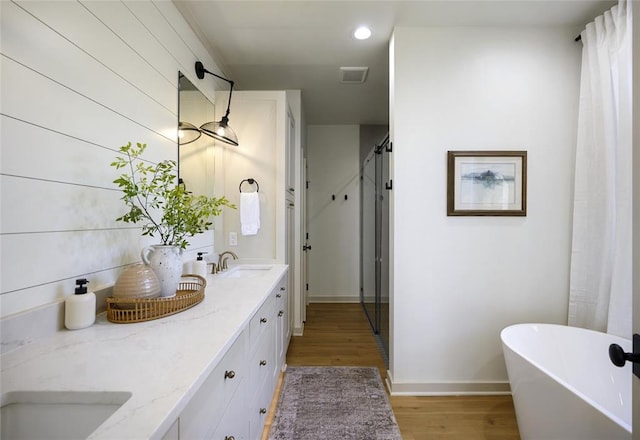 bathroom featuring a washtub, vanity, and wood-type flooring