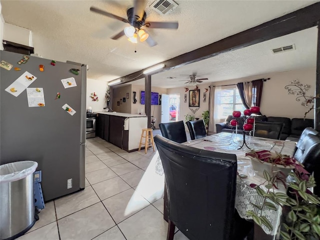 dining area with ceiling fan, beam ceiling, light tile patterned floors, and a textured ceiling