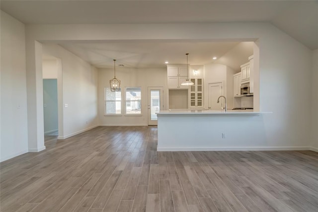 kitchen featuring white cabinetry, light hardwood / wood-style floors, decorative light fixtures, and a notable chandelier