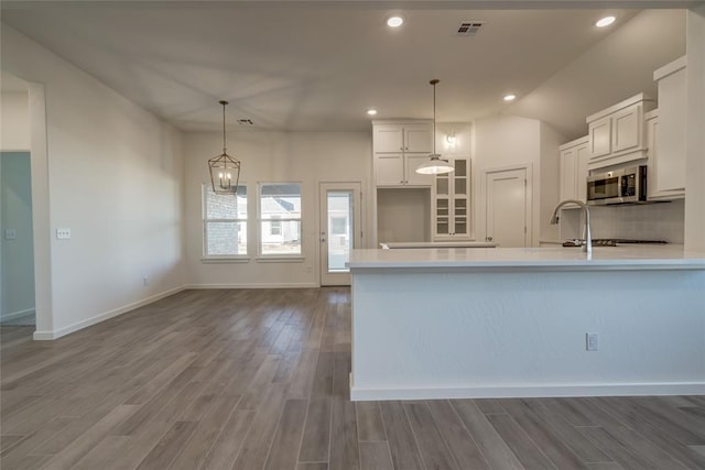 kitchen with hardwood / wood-style floors, a notable chandelier, backsplash, decorative light fixtures, and white cabinetry