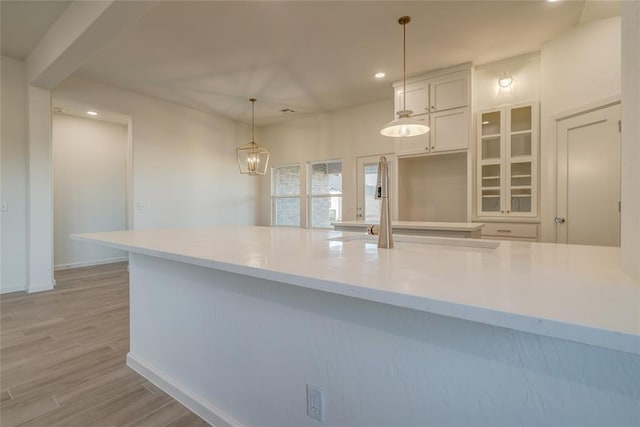 kitchen featuring white cabinetry, light hardwood / wood-style flooring, pendant lighting, and a notable chandelier