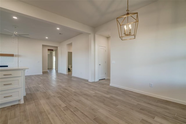 interior space featuring light hardwood / wood-style flooring and ceiling fan with notable chandelier