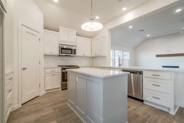 kitchen with a kitchen island, white cabinetry, appliances with stainless steel finishes, and tasteful backsplash