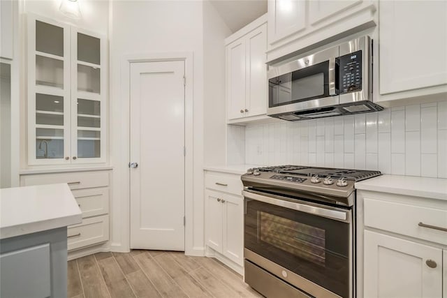 kitchen featuring white cabinets, decorative backsplash, and stainless steel appliances