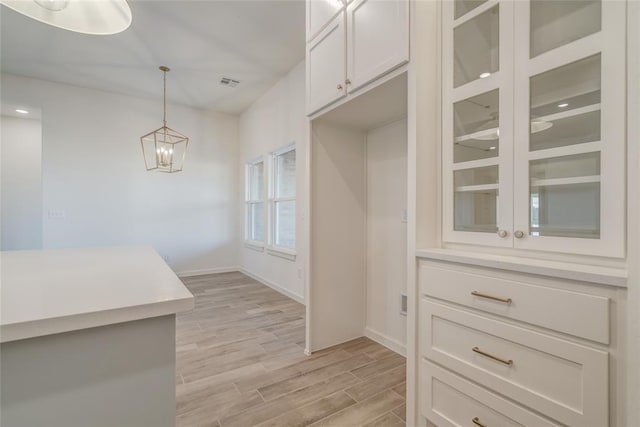 kitchen with light hardwood / wood-style flooring, white cabinets, and pendant lighting