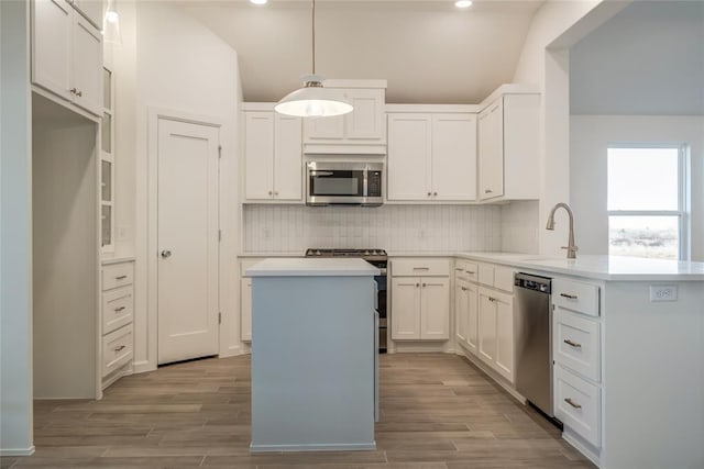 kitchen with decorative light fixtures, sink, white cabinetry, and stainless steel appliances