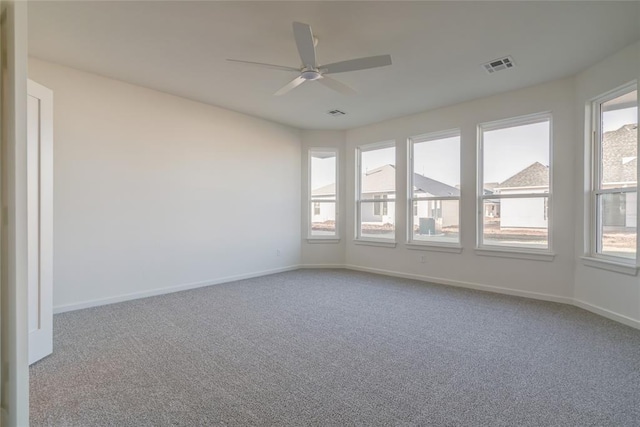 carpeted spare room featuring plenty of natural light and ceiling fan