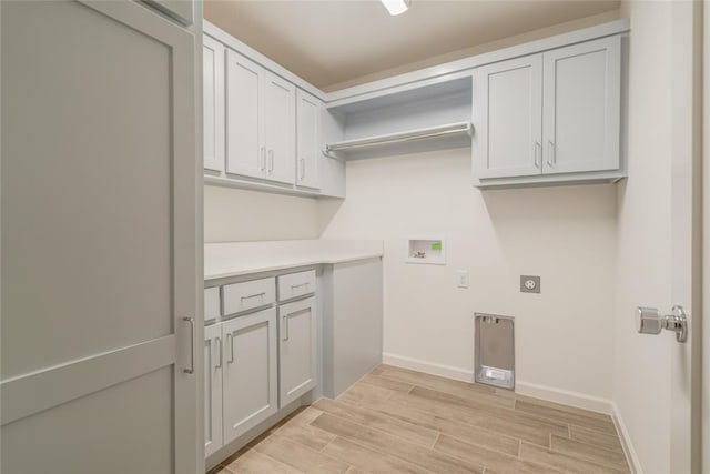 laundry area featuring electric dryer hookup, light hardwood / wood-style floors, cabinets, and washer hookup