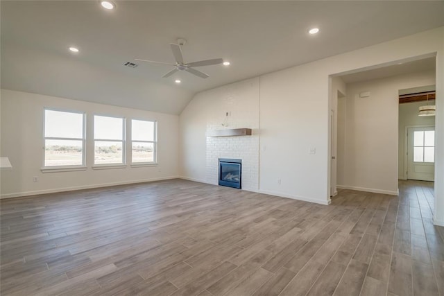 unfurnished living room with ceiling fan, a healthy amount of sunlight, light wood-type flooring, and a brick fireplace