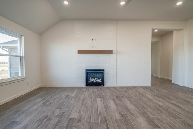 unfurnished living room featuring light hardwood / wood-style floors, lofted ceiling, and a fireplace