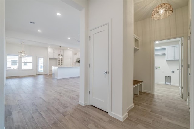 corridor with a chandelier and light hardwood / wood-style floors