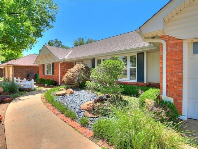 view of front of house featuring brick siding and a shingled roof