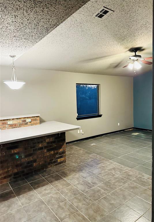 interior space featuring tile patterned floors, ceiling fan, and a textured ceiling