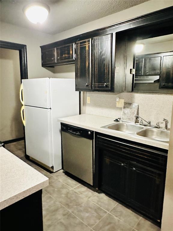 kitchen featuring dishwasher, white fridge, light tile patterned flooring, and sink