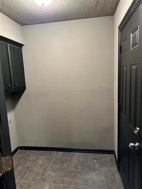 clothes washing area featuring a textured ceiling and dark tile patterned floors