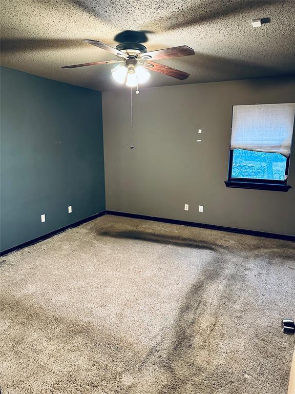 carpeted empty room featuring a textured ceiling and ceiling fan