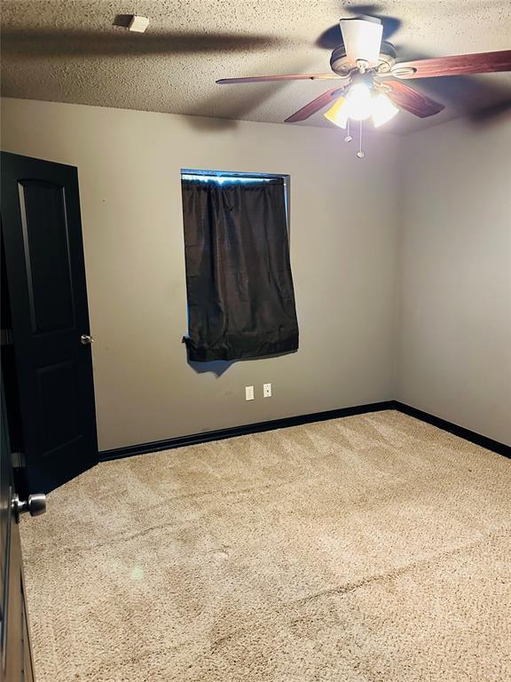 carpeted spare room with ceiling fan and a textured ceiling