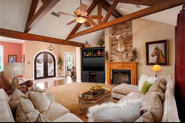 living room with hardwood / wood-style floors, high vaulted ceiling, french doors, a stone fireplace, and beam ceiling