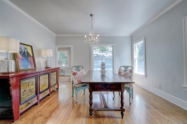 dining space with light hardwood / wood-style floors, an inviting chandelier, and ornamental molding