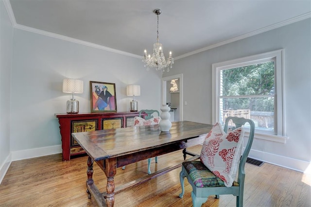 dining room featuring a notable chandelier, ornamental molding, and light hardwood / wood-style flooring