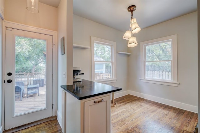 kitchen featuring white cabinets, light wood-type flooring, decorative light fixtures, and a wealth of natural light