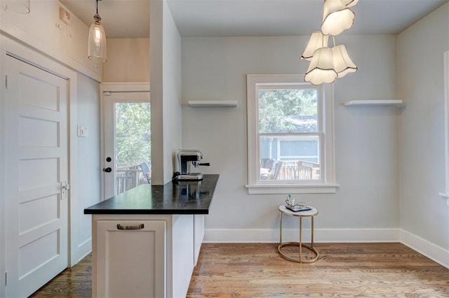 kitchen with white cabinets, a healthy amount of sunlight, light wood-type flooring, and pendant lighting