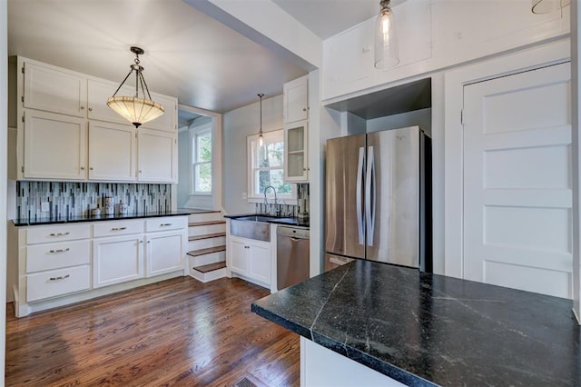 kitchen with white cabinets, sink, hanging light fixtures, decorative backsplash, and stainless steel appliances