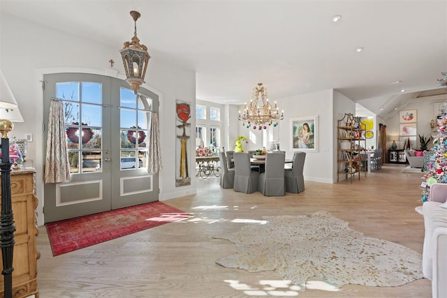 entrance foyer with french doors, light hardwood / wood-style flooring, an inviting chandelier, and lofted ceiling