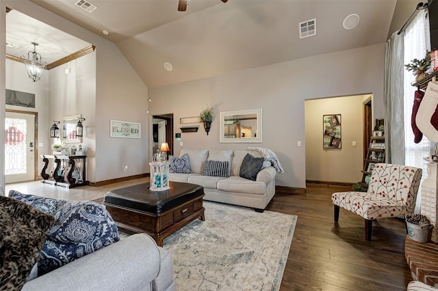 living room with hardwood / wood-style floors, high vaulted ceiling, and ceiling fan with notable chandelier