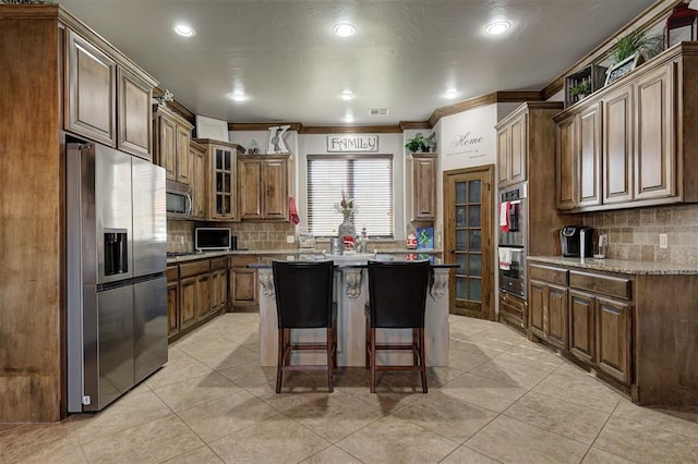 kitchen with a kitchen breakfast bar, backsplash, stainless steel appliances, crown molding, and a kitchen island