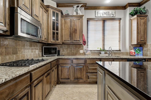 kitchen featuring light tile patterned flooring, appliances with stainless steel finishes, ornamental molding, and sink